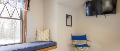Una habitación con ventanal, televisión y sillón de director.