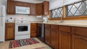 A kitchen with wooden cabinets, a white stove, a microwave, and a dishwasher. - CPE1-Lovely Chalet! A/C, Pets Ok! (Davis)