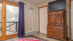 A room with a large window, a sliding door, a wooden dresser, and a flat-screen TV. - CPE1-Lovely Chalet! A/C, Pets Ok! (Davis)