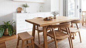 A modern kitchen with white cabinetry, a wooden dining table, and a woven pendant light. - Crystal Pacific Palm Beach (Palm Beach)