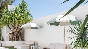 A poolside area with a white pool, green artificial grass, white lounge chairs, and umbrellas. - Crystal Pacific Palm Beach (Palm Beach)