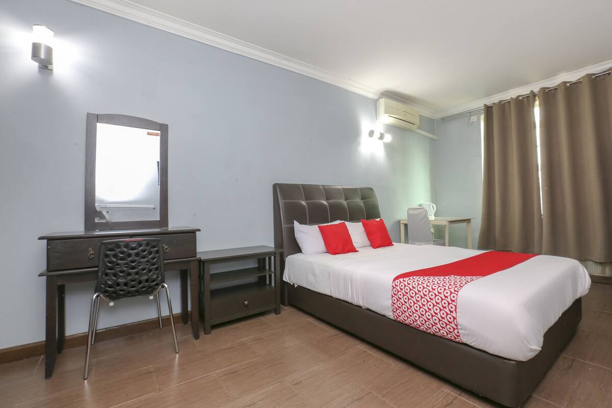 Una habitación de hotel con cama, escritorio, silla y espejo.