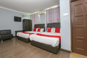 A hotel room with two beds, a TV, a wardrobe, and a door.