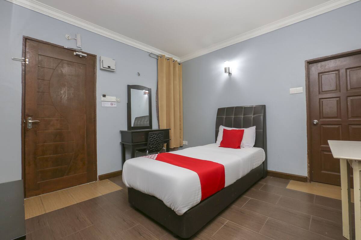 Habitación de hotel con cama, escritorio, silla y dos puertas.
