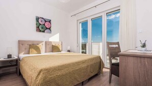A bedroom with a bed, a desk, a chair, a nightstand, a window with a view, and a painting on the wall. - Villa with pool, WiFi and air conditioning (Debeljak)