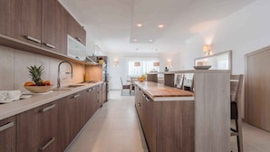 A modern kitchen with wooden cabinets, a central island, and pendant lighting. - Villa with pool, WiFi and air conditioning (Debeljak)