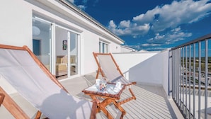 A balcony with two wooden lounge chairs, a small table with a decorative item, and a glass door leading to an interior room. - Villa with pool, WiFi and air conditioning (Debeljak)