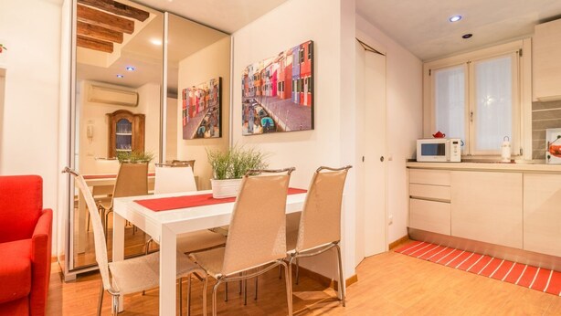 A modern kitchen with white cabinets, a microwave, and a red rug.