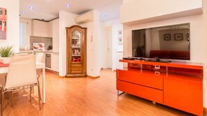 A modern kitchen with wooden cabinets, a red cabinet, and a dining area with a chair and table.