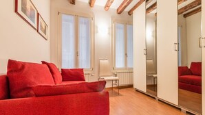 A modern living room with a red sofa, wooden beams on the ceiling, and large windows.
