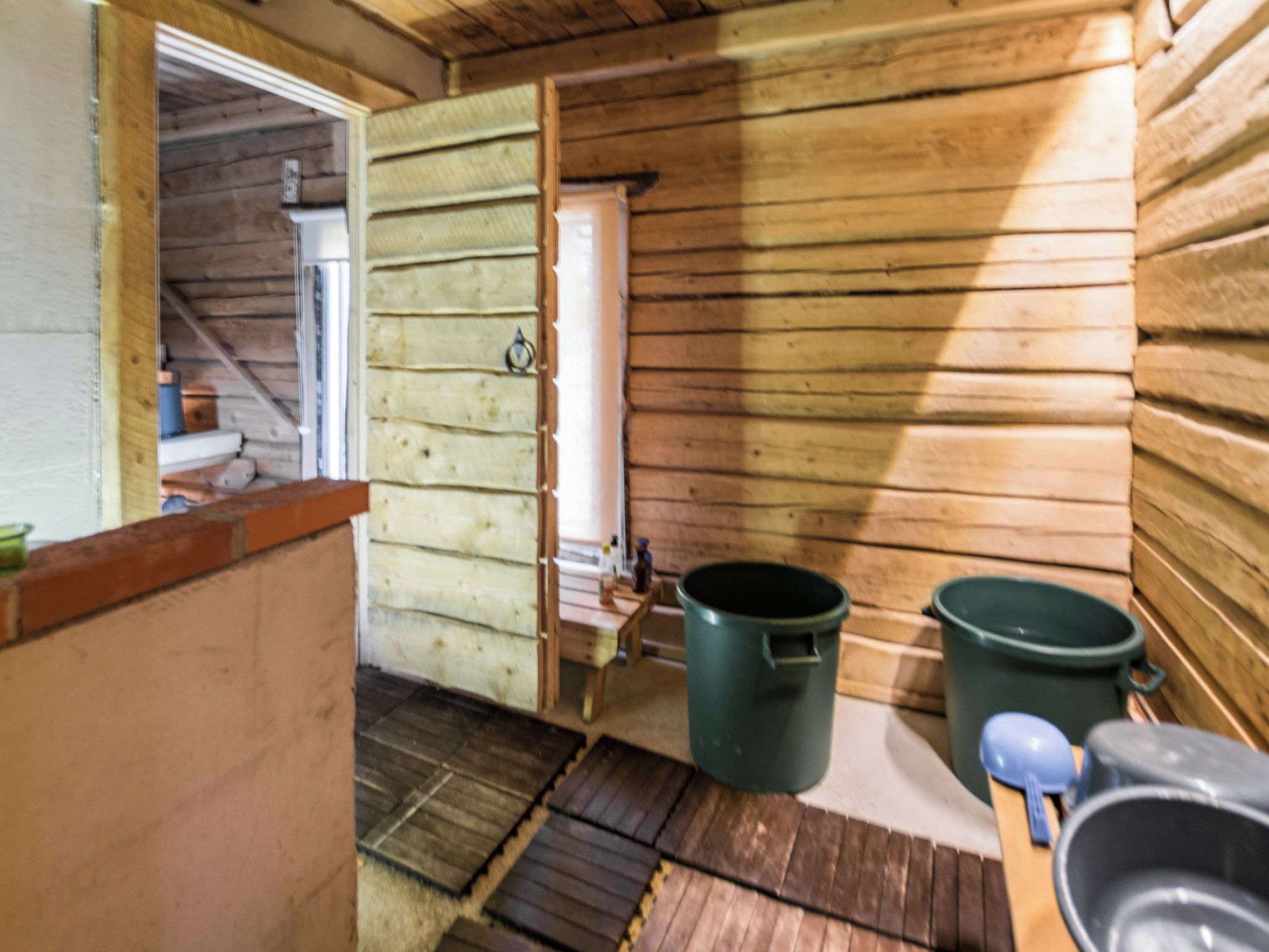 Een houten cabinne interieur met een deur, een raam en een houten vloer.