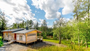 A wooden cabin with a porch, surrounded by lush greenery and a lake. - Vacation home Koivu by Interhome (Sonkajärvi)