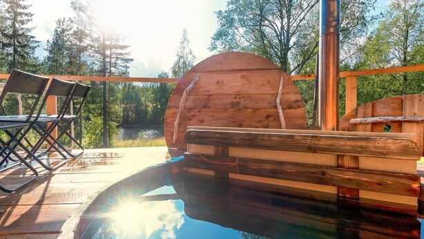 A wooden deck with a circular wooden structure, possibly a barrel, and a small pool reflecting trees. - Vacation home Koivu by Interhome (Sonkajärvi)