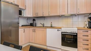 A modern kitchen with light wood cabinets, stainless steel appliances, and a wooden countertop.