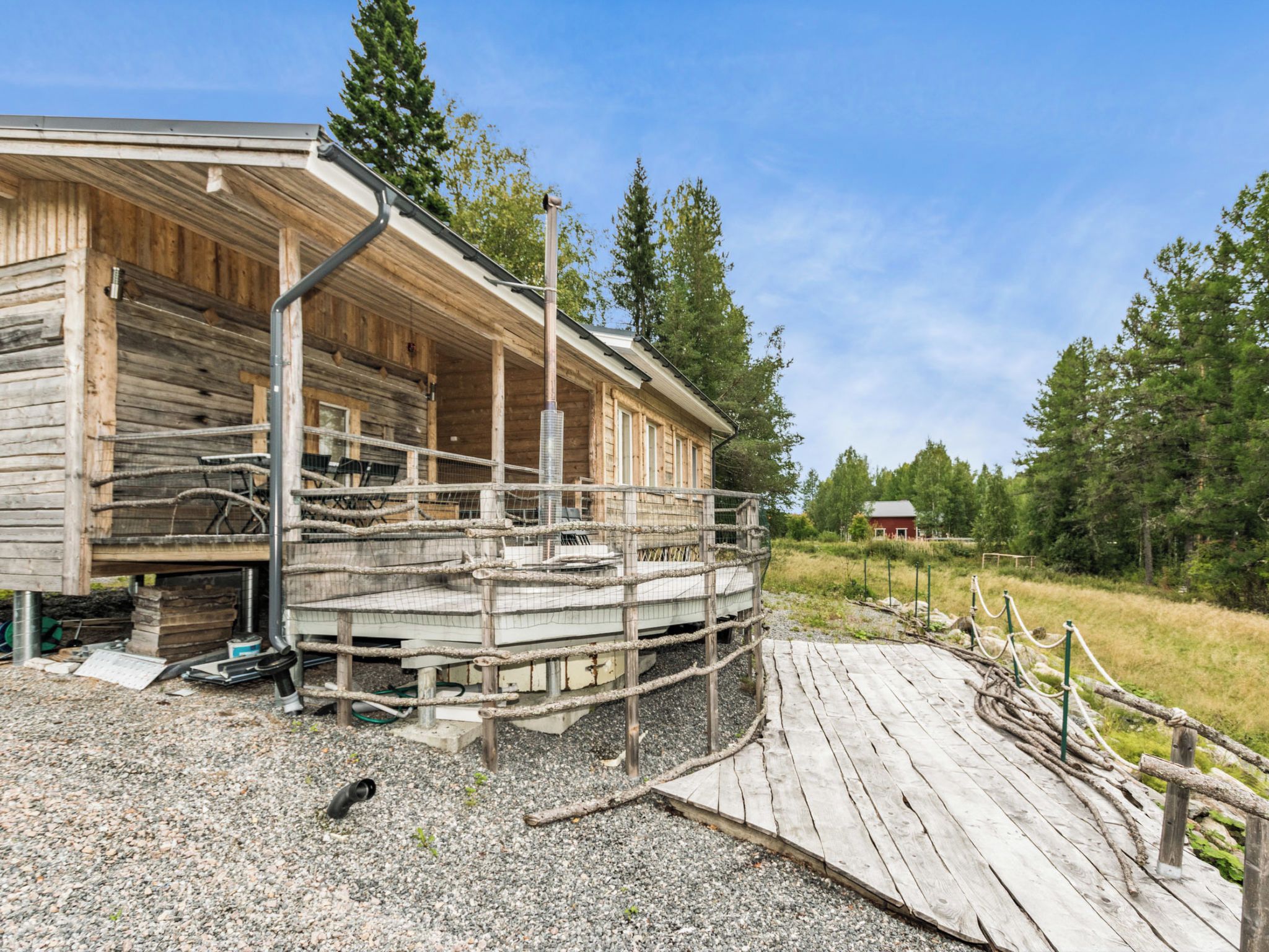 A wooden cabin with a porch and a gravel driveway.