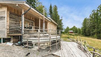 A wooden cabin with a porch and a gravel driveway.
