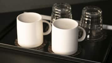 A tray with two white mugs and two clear glasses on a dark surface.