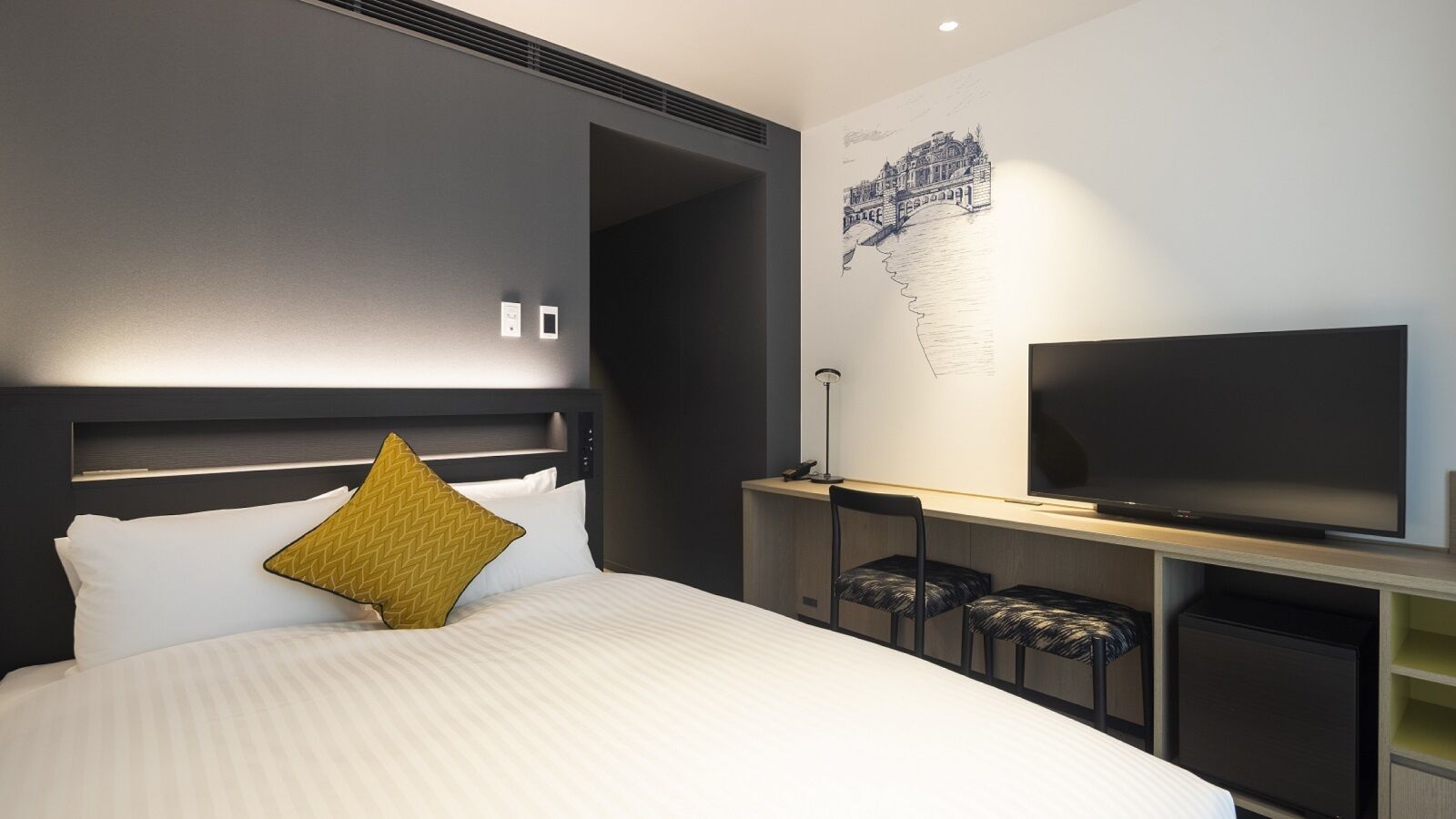 Ein modernes Hotelzimmer mit einem großen Bett, einem Flachbildfernseher, einem Schreibtisch mit Stuhl und einem Wandbild.