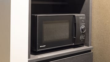Un forno a microonde con un pannello di controllo, posizionato su un ripiano in legno.