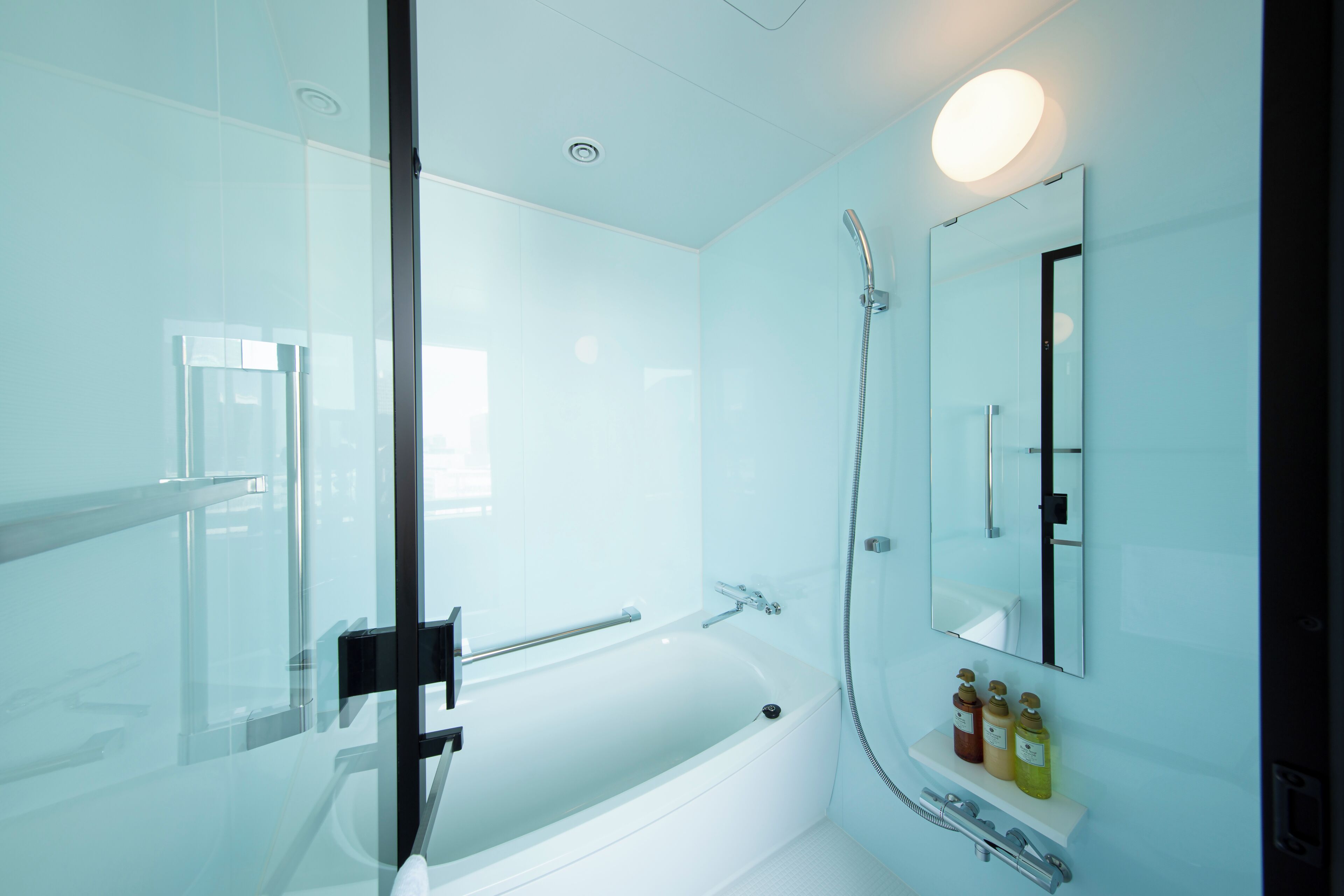 A modern bathroom with a glass shower enclosure, a white bathtub, and a mirror above the sink.