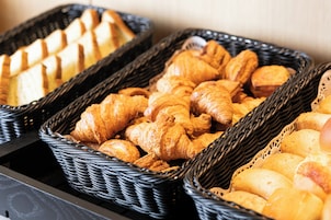 Three wicker baskets filled with various baked goods, likely for breakfast or snacks.