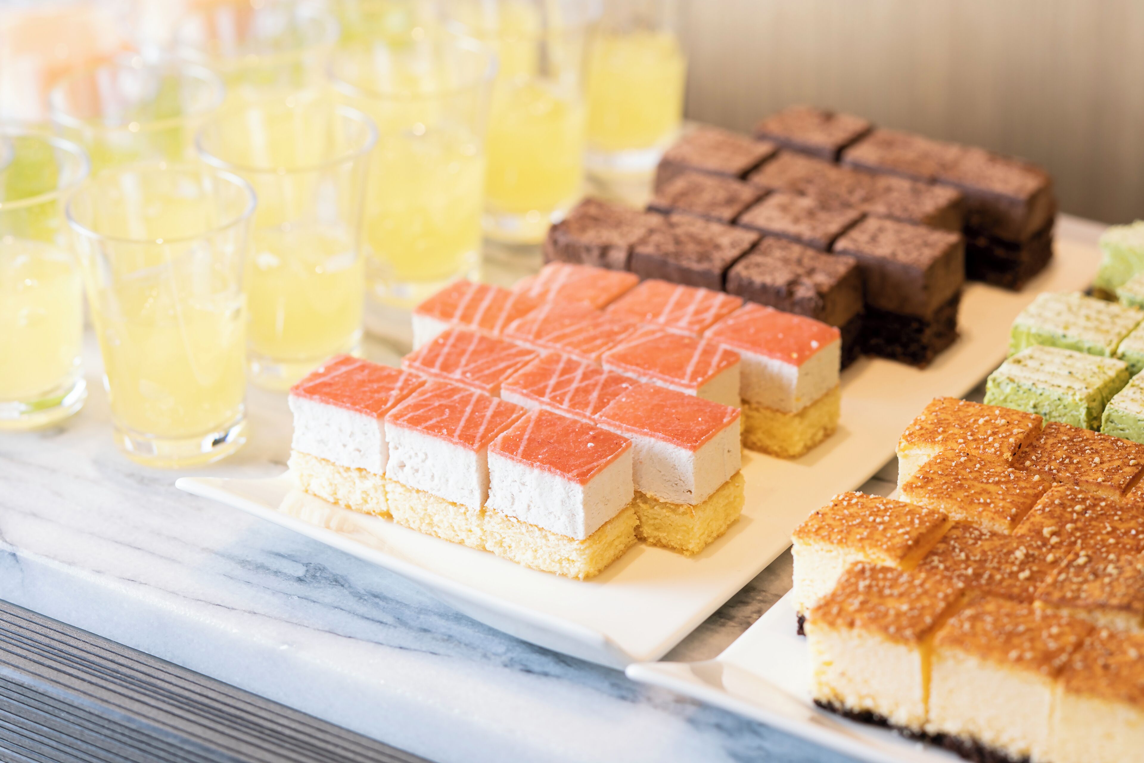 A variety of desserts and beverages on a marble table.