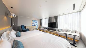 Ein modernes Hotelzimmer mit einem großen Bett, einem Fernseher, einer Couch und einem Esstisch.