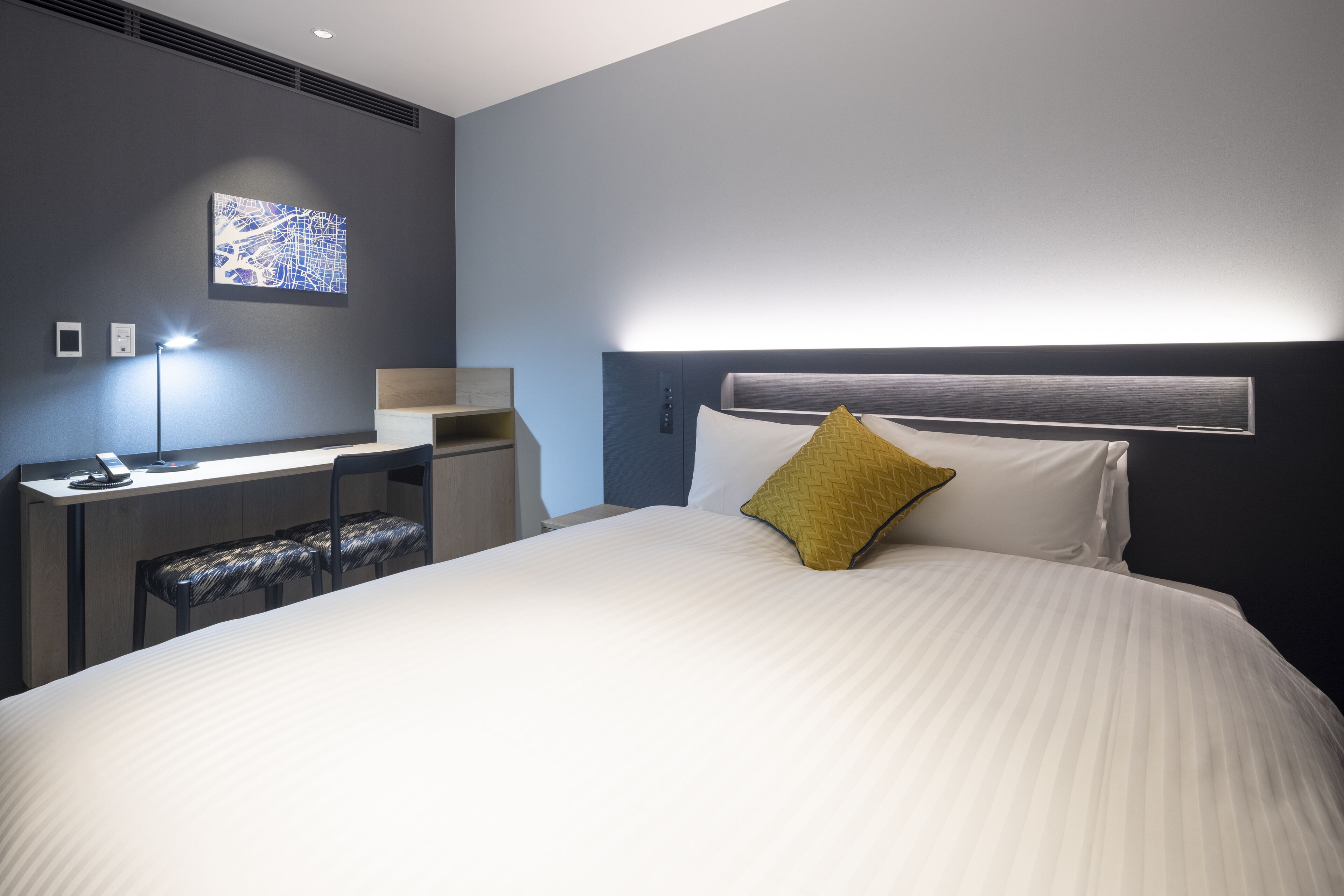 A modern hotel room with a large bed, a desk, and a chair.