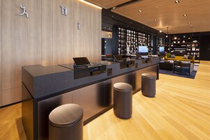 A modern reception desk with a counter, bar stools, and a seating area with a yellow sofa.