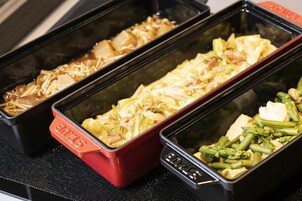Three rectangular food containers on a black tray.