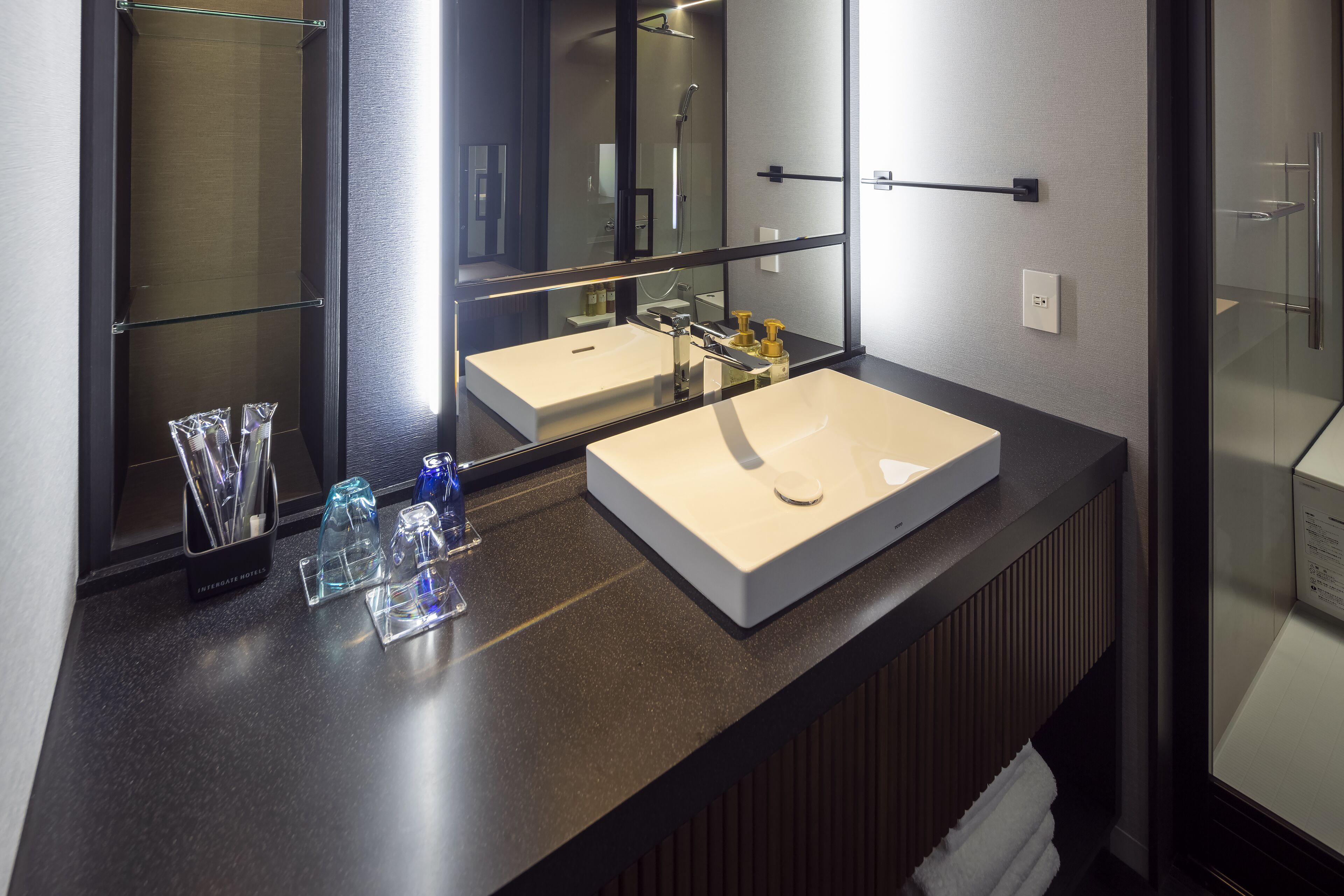A modern bathroom with a large mirror, two sinks, and a glass shower enclosure.