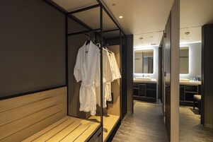 A hotel corridor with a wooden bench, a mirror, and a rack of white robes.