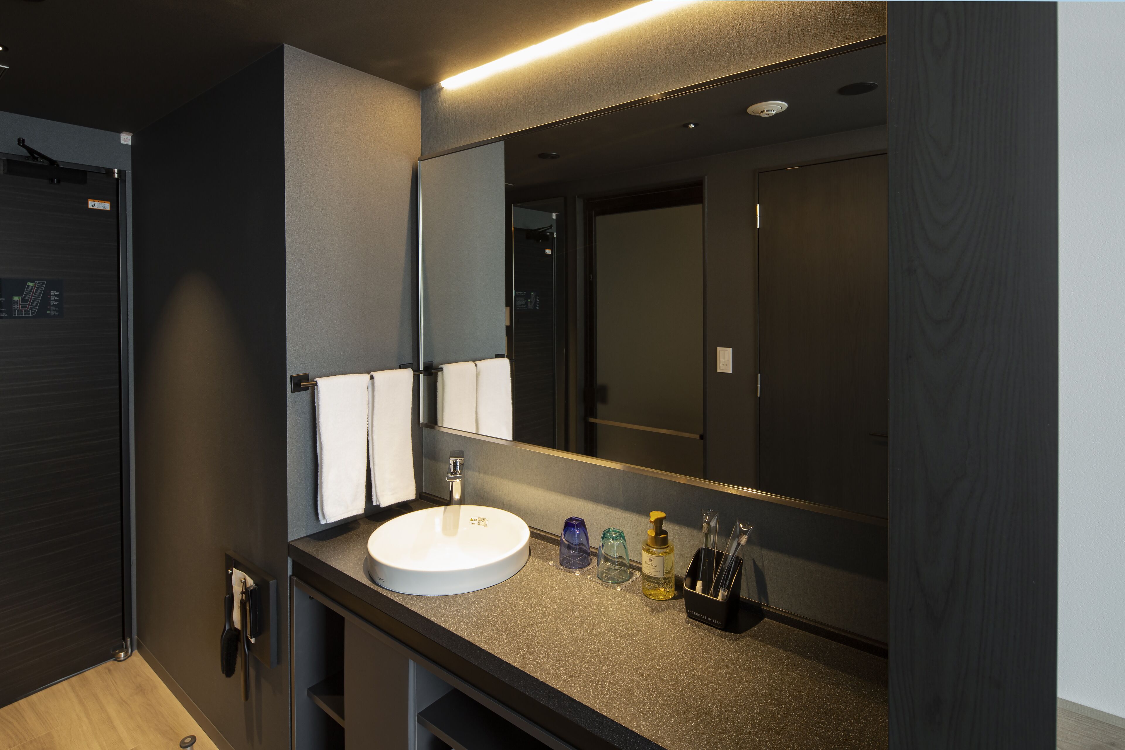 Un baño moderno con un lavamanos redondo, un espejo y un perchero para toallas.
