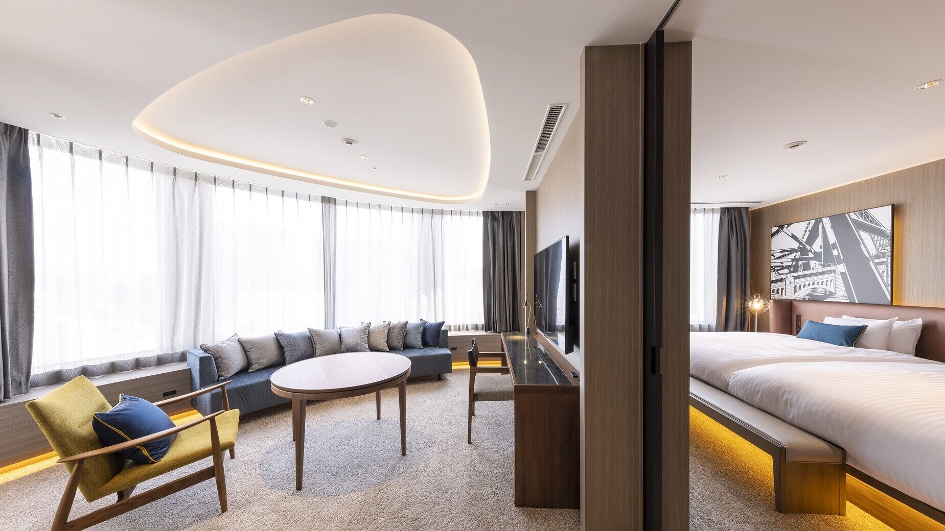 Ein modernes Hotelzimmer mit einem großen Bett, einer Couch, einem Fernseher und einem Essbereich.