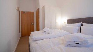 A hotel room with a bed, a wardrobe, and a door. - Double room economy - lodging house oystercatcher (Norderney)