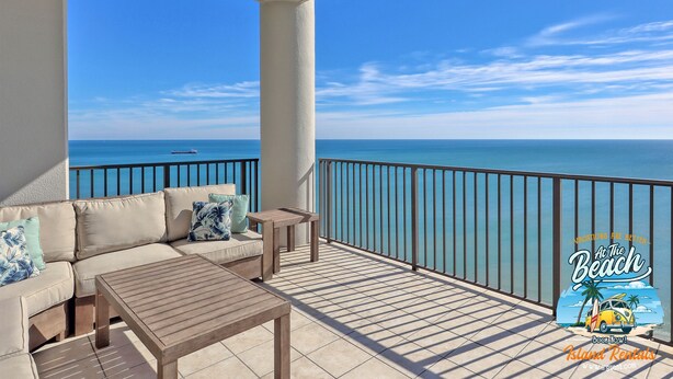 Een balkon met een bank, een klein tafeltje en uitzicht op de oceaan.