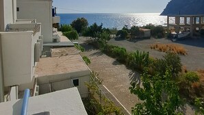 Een kustgezicht met heldere lucht, een zonovergoten zee en een gebouw met balkons met uitzicht op het strand.