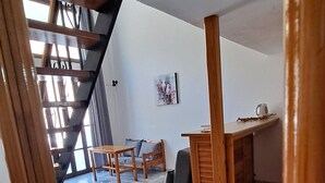 Een ruime woonkamer met een trap, een eettafel en een bank.