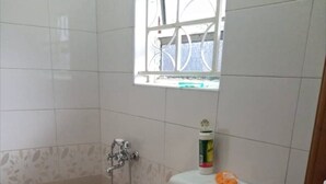 A small bathroom with a toilet, a shower, and a window. - Tranquil Corner Kampala (Kampala)