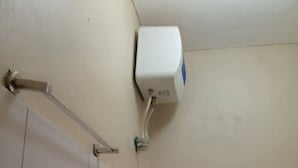 A corner of a room with a white tiled wall, a white air conditioning unit mounted on the wall, and a metal handrail attached to the wall. - Tranquil Corner Kampala (Kampala)