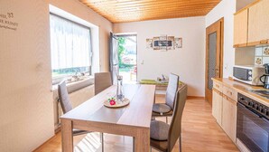 Cozinha moderna com armários de madeira, uma mesa de jantar com cadeiras e vista para o exterior.