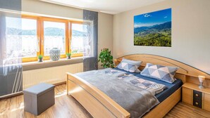 Quarto moderno com uma cama grande, vista para o exterior através de uma janela e um quadro na parede.