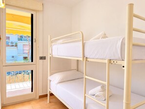 Une chambre avec des lits superposés et une fenêtre donnant sur un immeuble.
