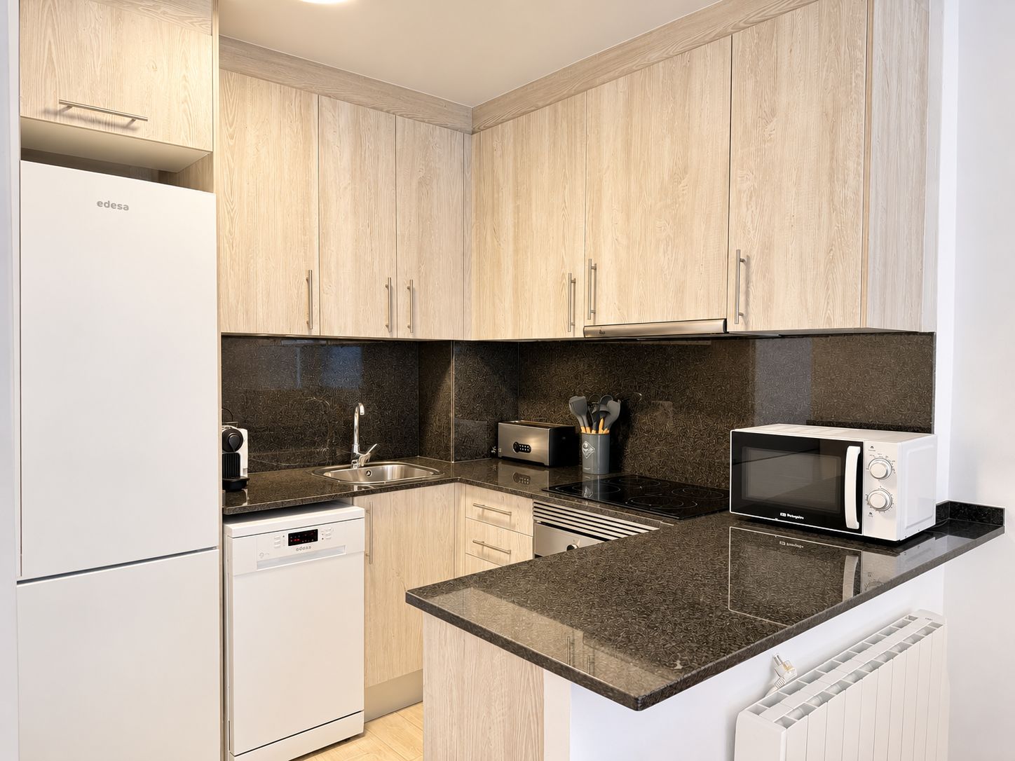 A modern kitchen with wooden cabinets, a dishwasher, a stove, a microwave, and a toaster.