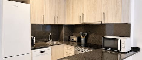 A modern kitchen with wooden cabinets, a dishwasher, a stove, a microwave, and a toaster.