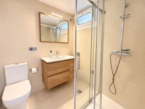 Ein modernes Badezimmer mit Toilette, Waschbecken, Waschtisch und Duschkabine.
