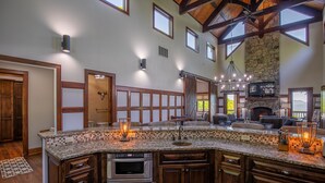 A spacious kitchen with a large island, built-in oven, and stone fireplace.