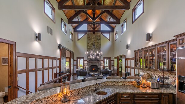 A spacious kitchen with a large island, built-in appliances, and a stone fireplace.