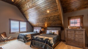 Une chambre avec deux lits, un plafond en bois, une commode et une fenêtre donnant sur un beau paysage.