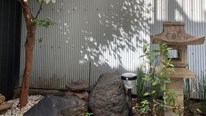 A garden with a stone lantern, a tree, and a metal structure. - Platinum Yasaka (Kyoto)
